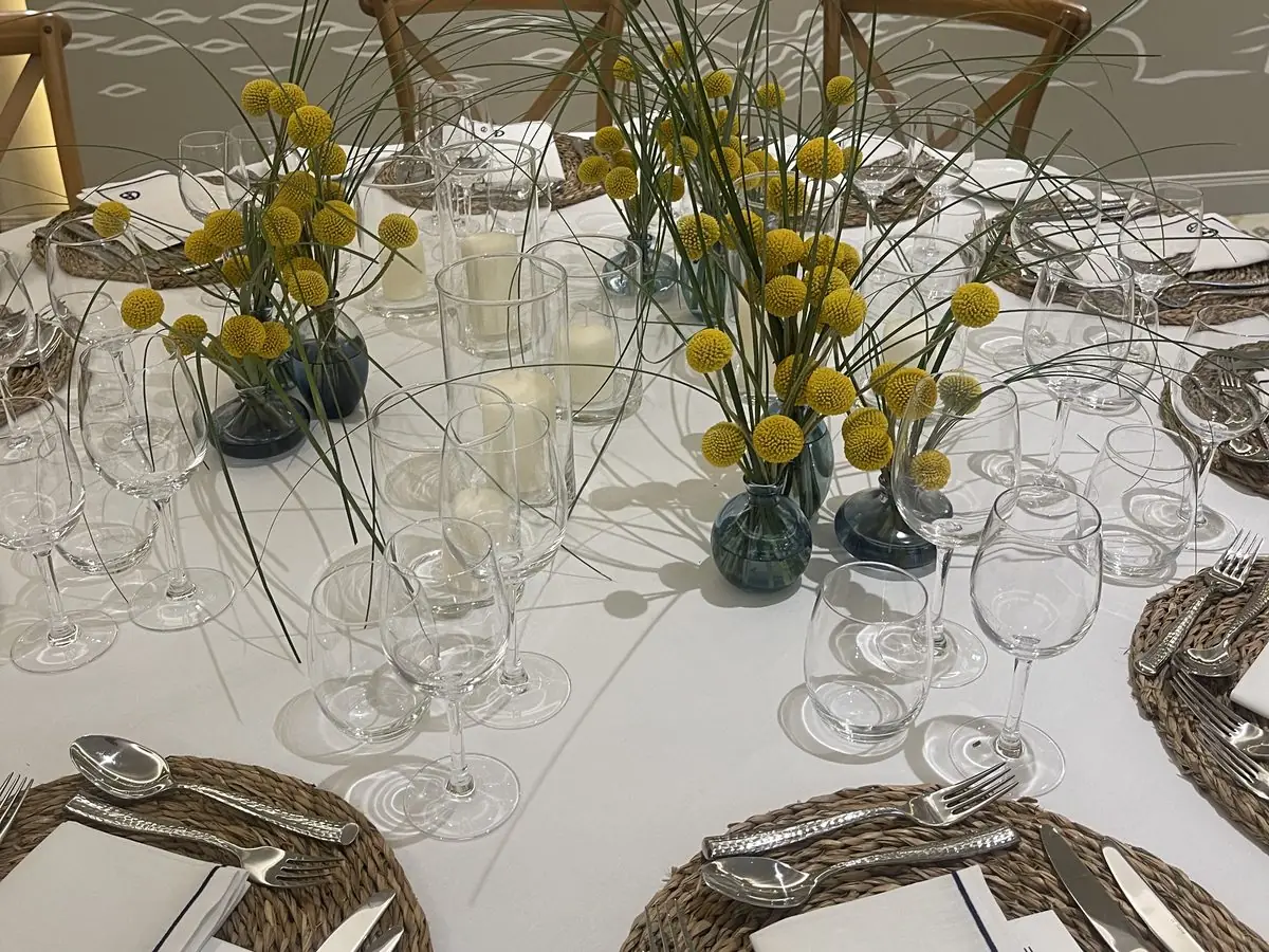 Table de dîner dressée en extérieur, nappe bleue et fleurs jaunes